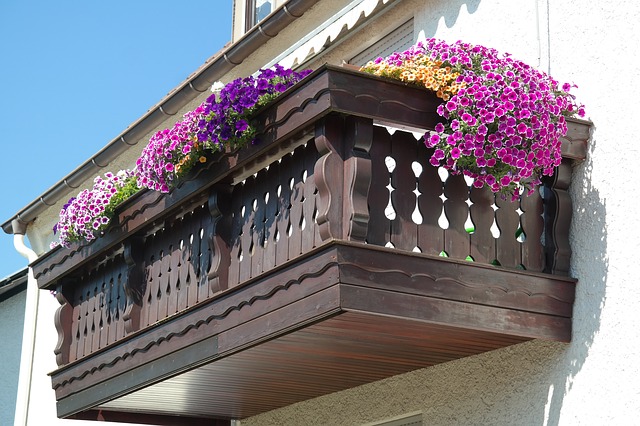 Ein freitragender Balkon aus Holz hängt an einer hellen Hauswand.