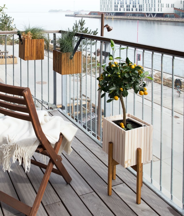 Ein Balkon mit Blick auf einen Fluss. Er ist mit verschiedenen Pflanzkübeln aus Holz und einem Stuhl bestückt.
