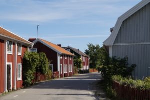 Eine Straße biegt um die Kurve, auf ihr reihen sich viele traditionelle Schwedenhäuser aneinander