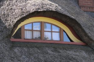 Eine runde Dachgaube, welche mit Reet gedeckt ist.