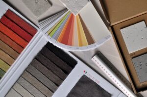 Auf einem Tisch liegen einige Materialien, mit denen zum Beispiel ein Innenarchitekt arbeiten würde: Farbkarten, Stoffproben, Bodenbeläge.